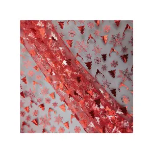 Tela de malla navideña estampada en rojo con copos de nieve para vestidos de fiesta y decoración.