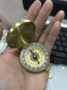 Detail shot of vintage brass pocket compass dial showing clear degree scales and directions.