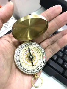 Vintage brass pocket compass with flip cover, portable outdoor survival navigation tool.