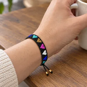 Close-up of handmade glass bead bracelet with colorful heart patterns and adjustable cord.