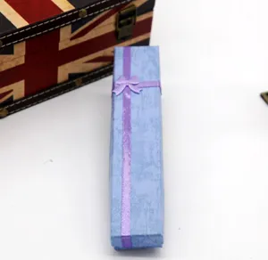 Close-up of a light blue long paper jewelry gift box featuring a purple ribbon bow detail.