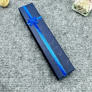 Detailed view of a long dark blue gift box with a bright blue ribbon bow for jewelry.