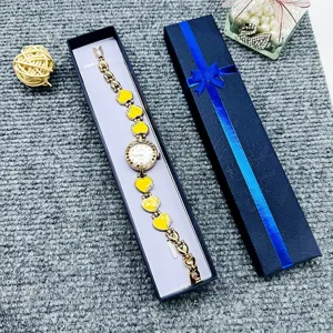 Gold quartz watch with yellow heart links and blue gift box, elegant detail view.