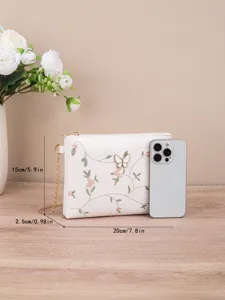 Detailed view of the white embroidered shoulder bag featuring delicate floral vines and butterfly.