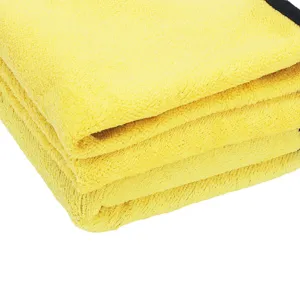 Primo piano del panno in microfibra giallo spesso per auto con bordo nero e morbida peluche.