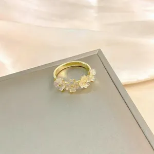 Close-up detail of the exquisite gold-plated ring featuring translucent floral resin accents.