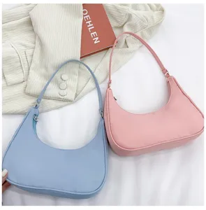 Detail view of stylish half-moon shoulder bags showcasing pastel pink and light blue colors.