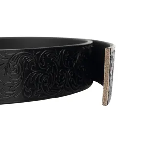Detailed shot of a black vintage embossed leather belt with intricate floral scrollwork pattern.