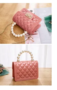 Pink quilted jelly mini bag with pearl handle and gold chain strap, detailed product view.
