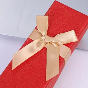 Caja de regalo roja para bolígrafos con lazo dorado, elegante envase para plumas y regalos.