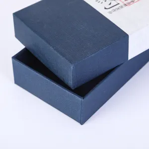 Detalle de caja de regalo azul con funda de papel de caligrafía blanca, empaque.