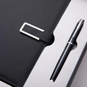 Detalle en primer plano de un lujoso juego de regalo con cuaderno de cuero negro y bolígrafo.