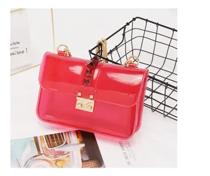 Transparent PVC jelly shoulder bag featuring gold chain strap, metal lock and chic pyramid studs.