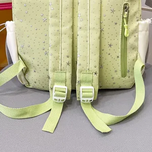 Detailed view of the light green backpack back with silver star patterns and adjustable straps.