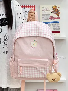 Detailansicht des rosa karierten Schulrucksacks mit süßer Apfelstickerei und Bärenanhänger.