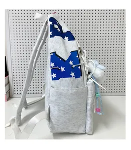 Detailansicht des lässigen grauen Rucksacks mit Sternbuchstaben, Seitentasche und Anhänger.