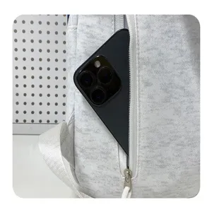 Nahaufnahme des seitlichen Reißverschlussfachs des grauen Stoffrucksacks mit Smartphone.