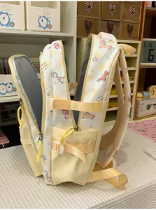 Detail view of the light yellow school backpack featuring cute pony patterns and side pockets.