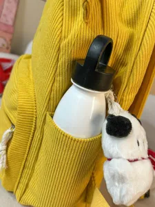 Yellow corduroy backpack for women, casual school bag with cute cartoon plush toy pendant.