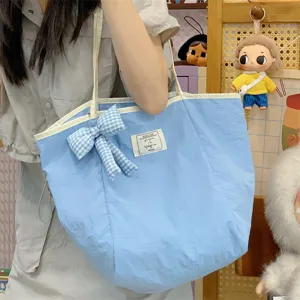 Λεπτομέρεια τσάντας shopper από μπλε ναϊλον με καρό φιόγκο κρεμαστό αξεσουάρ.