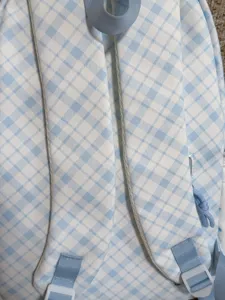 Light blue and white plaid backpack straps close-up, casual student schoolbag detail view.