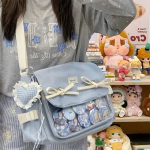 Detail shot of light blue ita bag featuring transparent window, cute bows and comfortable strap.