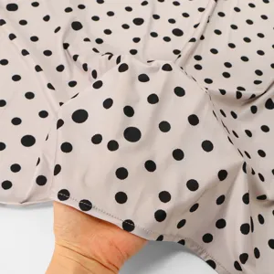 Close-up of soft polka dot fabric texture, lightweight material showing fine detail.
