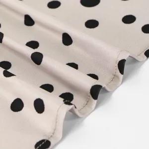 Close-up detail of soft polka dot scarf, showing delicate fabric texture and fine stitched edges.