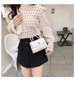 Detail view of a white quilted crossbody bag with metal twist lock, elegant design for women.