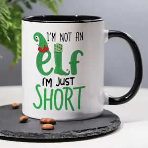 Primer plano de una taza de cerámica con divertida cita de elfo y granos de café decorativos.