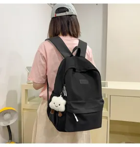 Detailed shot of a minimalist black casual backpack with cute pendant for students daily use.