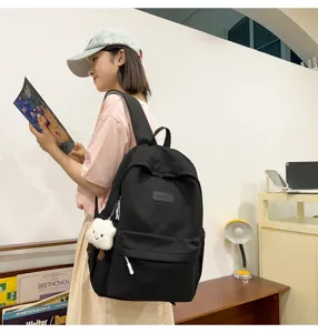Simple black casual backpack for women, large capacity school bag with front pocket and cute pendant.