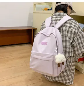 Detail view of a minimalist light purple casual backpack with a cute plush cloud pendant.