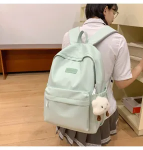 Minimalist light green backpack detail view showing front pocket and cute cloud pendant.
