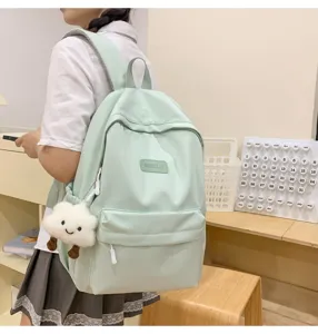 Close-up view of the light green casual backpack featuring side pendant and front pocket design.