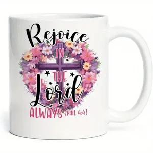 Primer plano detalle de taza de café de cerámica blanca con cruz floral y texto bíblico.