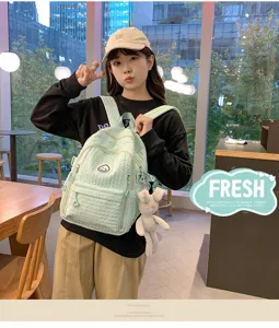 Detail view of a sweet soft girl light green backpack with cute smiley patch and plush rabbit pendant.