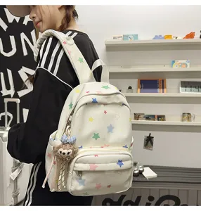 Vista detallada de la mochila blanca con estrellas de colores y bonito colgante de peluche.