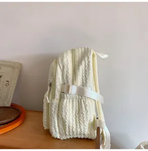 Side view of a minimalist sweet puffy backpack in creamy white, showing detailed texture and strap.