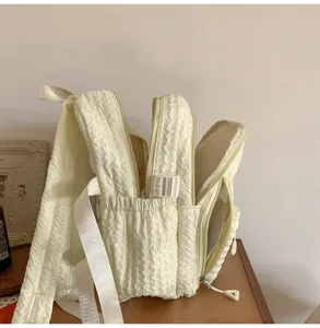 Detailed view of a light yellow quilted multi-compartment casual daily student backpack.