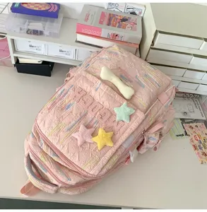 Pink casual backpack detail showing cute plush star bone charms and textured fabric design.