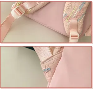Pink backpack strap detail view showing embossed pattern and colorful embroidery stitches.