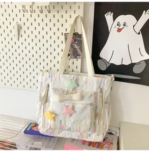 Detailed view of white canvas tote bag with colorful threads and cute plush star charms.