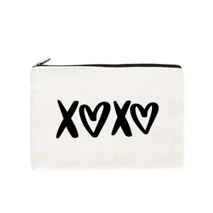 Primer plano detallado del estuche de lona blanca con estampado de corazones negros y cremallera.