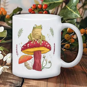 Nahaufnahme einer weißen Keramiktasse mit süßem Frosch und Pilz Grafikdesign Detailansicht.