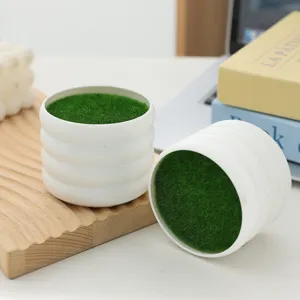 White ridged decorative pot with green grass filling, ideal for modern desktop plant display.