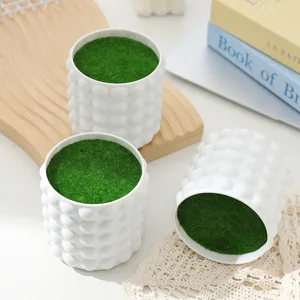 Detail view of white bubble textured flower pot filled with green moss desktop decor.