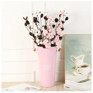 Detail view of artificial cotton flowers in pink metal bucket home decor display.