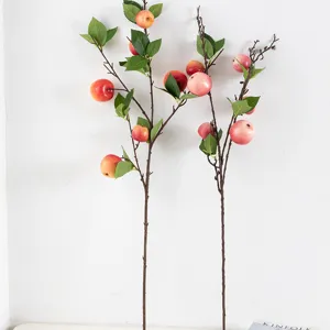 Artificial apple branches detail shot, lifelike red fruit and green leaves for home decor.