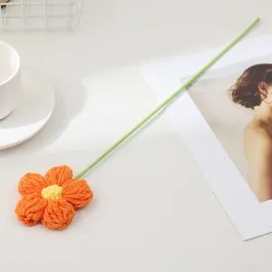 Handmade knitted crochet orange flower with green stem decorative ornament for home desktop decor.